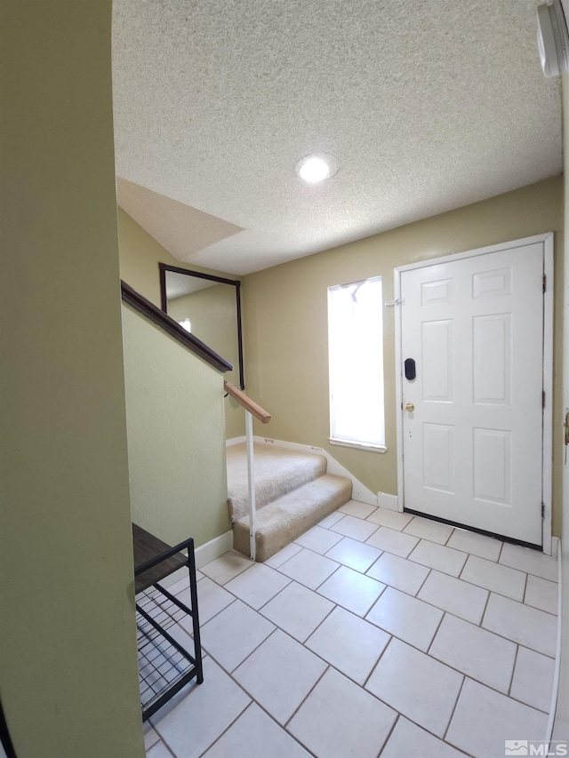 foyer featuring light tile patterned floors and a textured ceiling