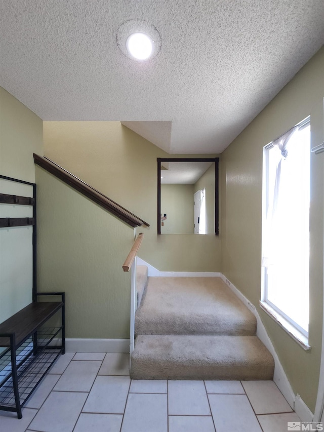 stairway with tile patterned flooring and a textured ceiling