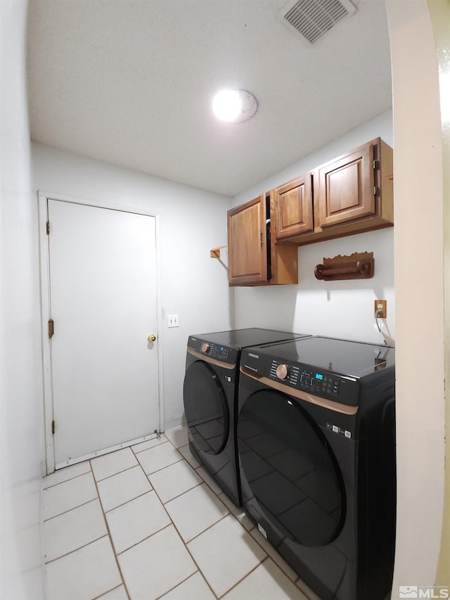 washroom with washer and dryer, light tile patterned floors, and cabinets