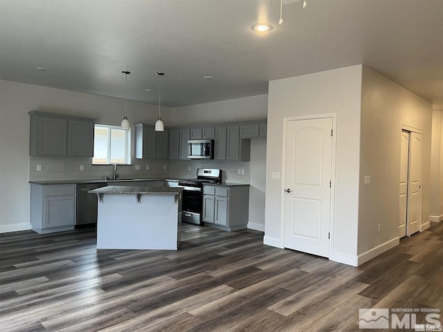 kitchen with a center island, hanging light fixtures, stainless steel appliances, dark hardwood / wood-style floors, and gray cabinets