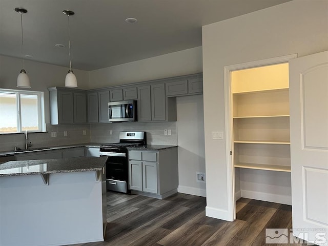 kitchen featuring dark stone counters, sink, decorative backsplash, dark hardwood / wood-style flooring, and stainless steel appliances