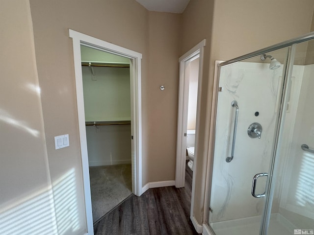 bathroom featuring hardwood / wood-style flooring, toilet, and a shower with shower door