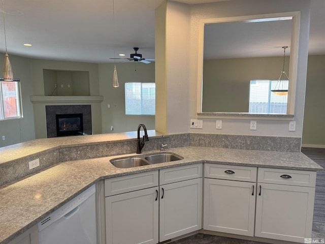 kitchen featuring a fireplace, white cabinetry, dishwasher, and sink