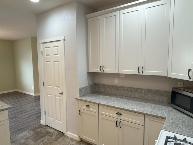 kitchen with white cabinetry, light stone countertops, and dark hardwood / wood-style flooring