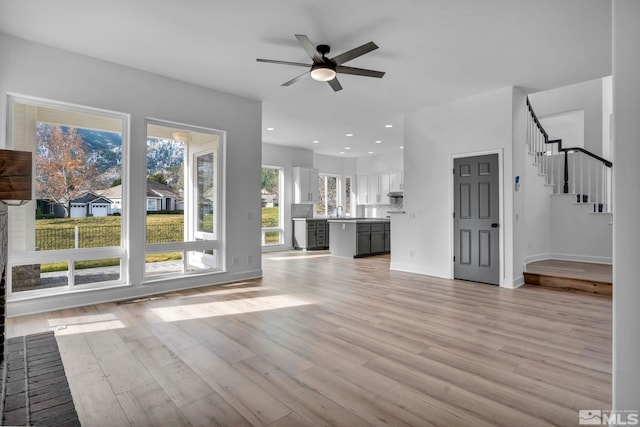 unfurnished living room featuring ceiling fan, light hardwood / wood-style floors, and sink