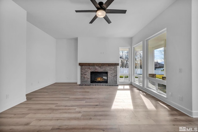 unfurnished living room featuring ceiling fan, light hardwood / wood-style floors, and a brick fireplace