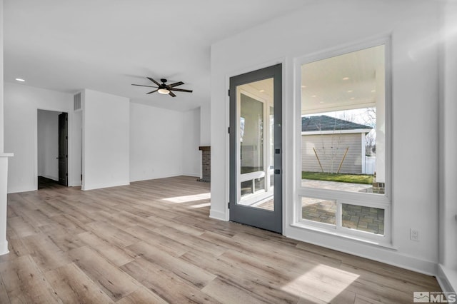 unfurnished living room featuring ceiling fan, light hardwood / wood-style flooring, and a brick fireplace