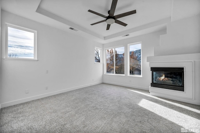 unfurnished living room featuring a multi sided fireplace, ceiling fan, plenty of natural light, and carpet flooring