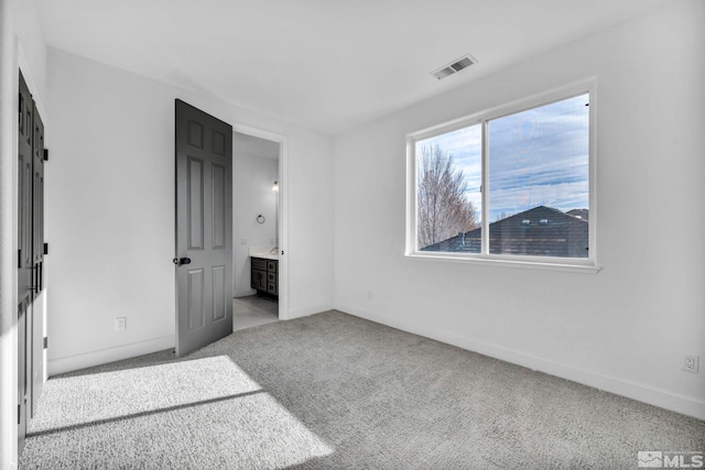 unfurnished bedroom featuring light colored carpet and connected bathroom