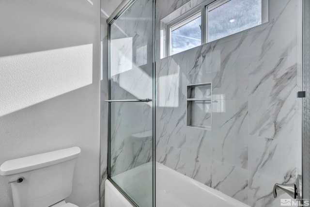 bathroom featuring combined bath / shower with glass door and toilet