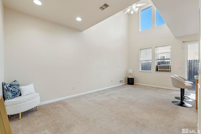 interior space featuring ceiling fan, light colored carpet, and a high ceiling