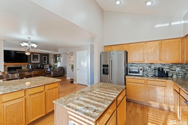 kitchen featuring a center island, light hardwood / wood-style flooring, light stone countertops, appliances with stainless steel finishes, and a chandelier