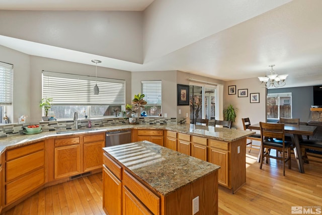 kitchen with sink, a center island, hanging light fixtures, and light wood-type flooring