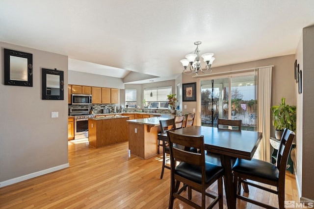 dining room featuring a healthy amount of sunlight, light wood-type flooring, and a chandelier