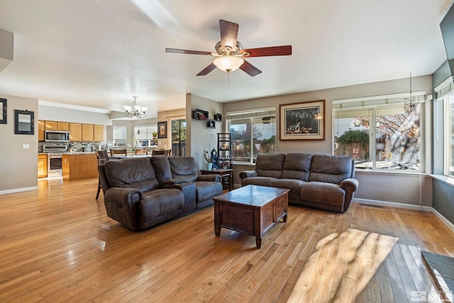 living room with ceiling fan with notable chandelier, a healthy amount of sunlight, and light hardwood / wood-style floors