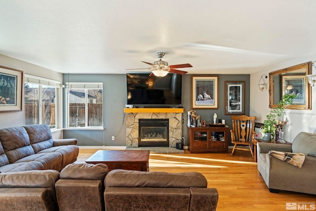 living room with ceiling fan, a fireplace, and light hardwood / wood-style floors