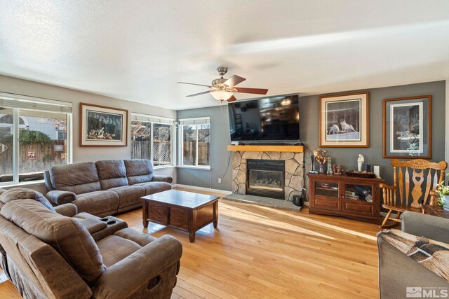 living room featuring ceiling fan, light hardwood / wood-style floors, and a fireplace