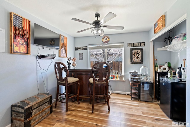 bar with ceiling fan and wood-type flooring