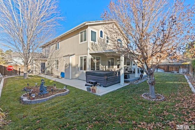 back of property with a lawn, a patio, and a hot tub