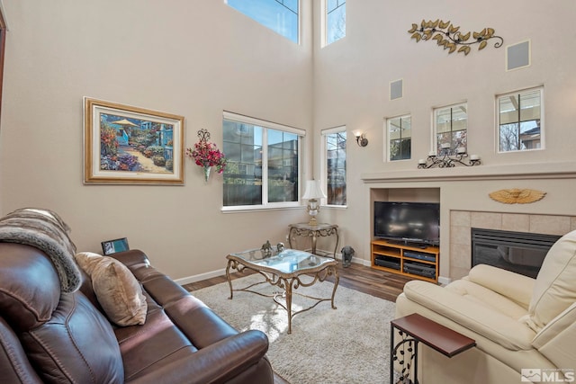 living room featuring a fireplace, a wealth of natural light, hardwood / wood-style floors, and a high ceiling