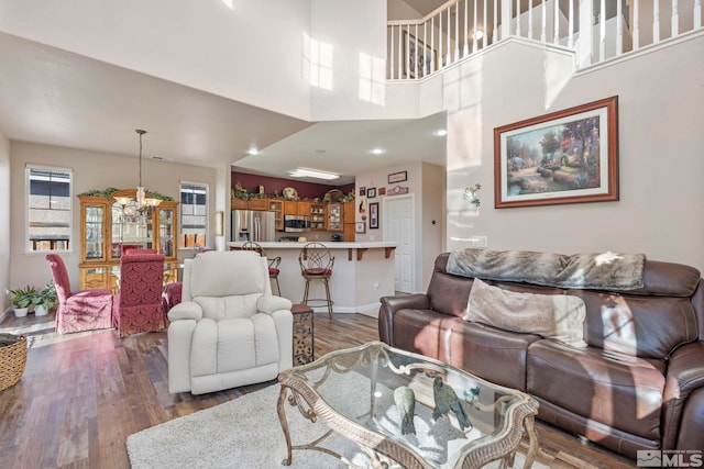 living room featuring dark hardwood / wood-style flooring, a high ceiling, and an inviting chandelier