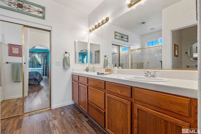 bathroom with walk in shower, vanity, and hardwood / wood-style flooring