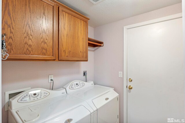 clothes washing area featuring washing machine and dryer, cabinets, and a textured ceiling