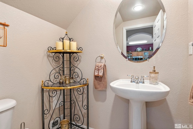 bathroom featuring sink, lofted ceiling, and toilet