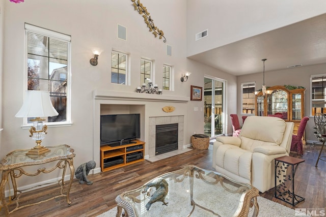 living room with dark wood-type flooring, a tile fireplace, and a high ceiling