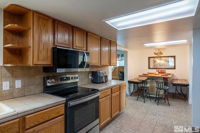 kitchen featuring tile countertops, decorative backsplash, and stainless steel appliances