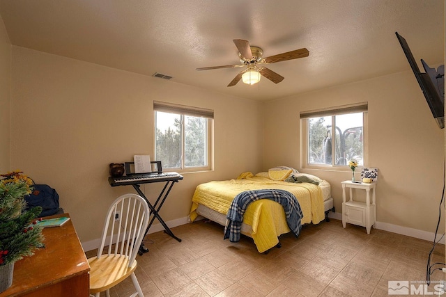 bedroom with ceiling fan and a textured ceiling