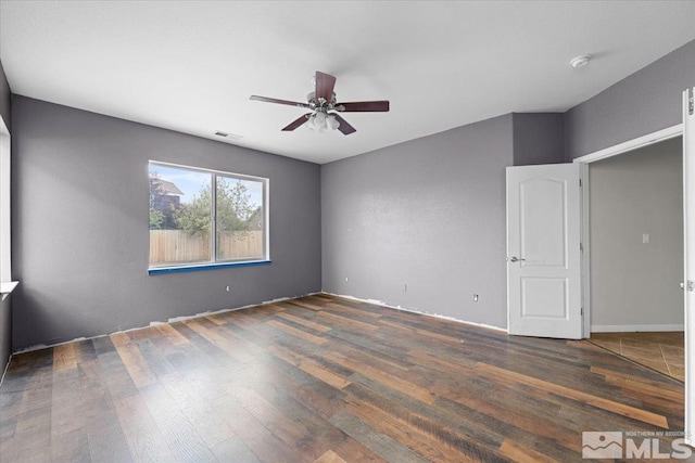 unfurnished room featuring wood-type flooring, a ceiling fan, baseboards, and visible vents