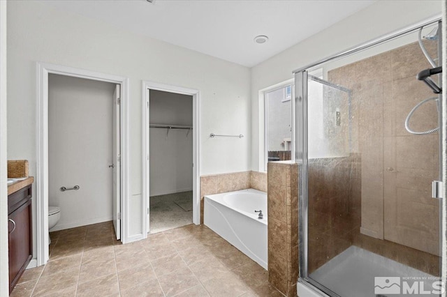 bathroom with a walk in closet, a bath, toilet, and a shower stall