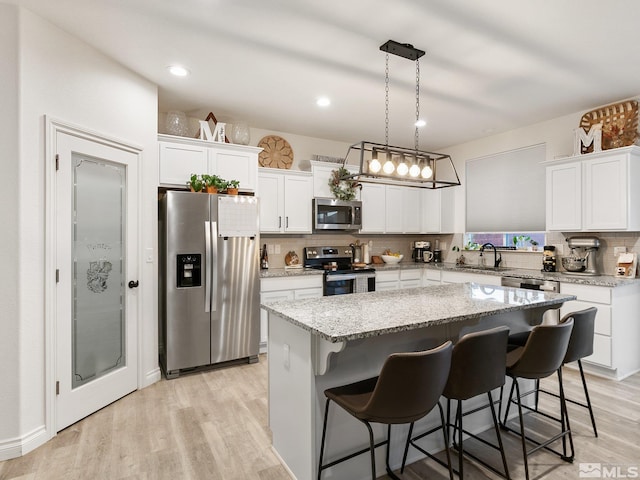 kitchen with pendant lighting, a center island, stainless steel appliances, and white cabinetry