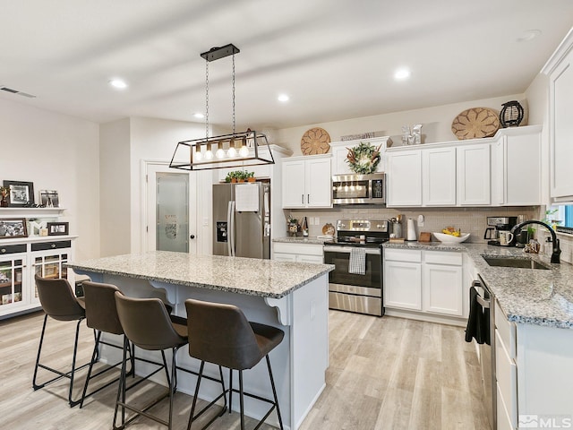 kitchen with white cabinets, sink, a kitchen island, and appliances with stainless steel finishes