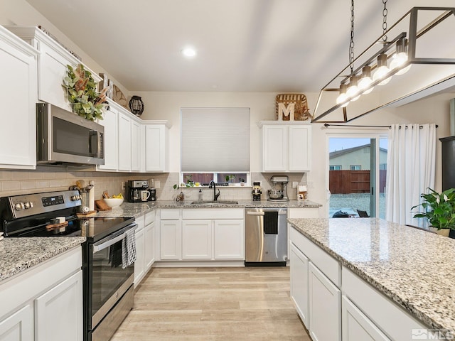 kitchen with sink, white cabinetry, stainless steel appliances, and hanging light fixtures