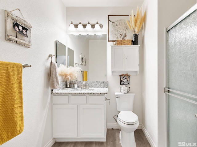 bathroom featuring hardwood / wood-style floors, vanity, toilet, and walk in shower