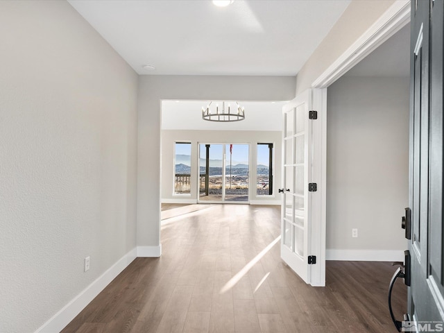 corridor with a chandelier and dark wood-type flooring