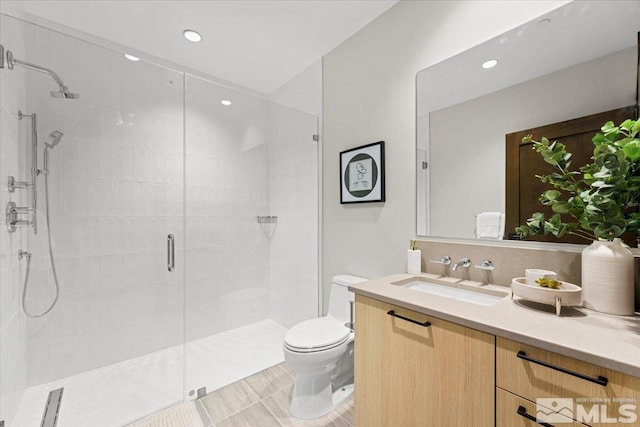 bathroom with tile patterned flooring, vanity, a shower with shower door, and toilet