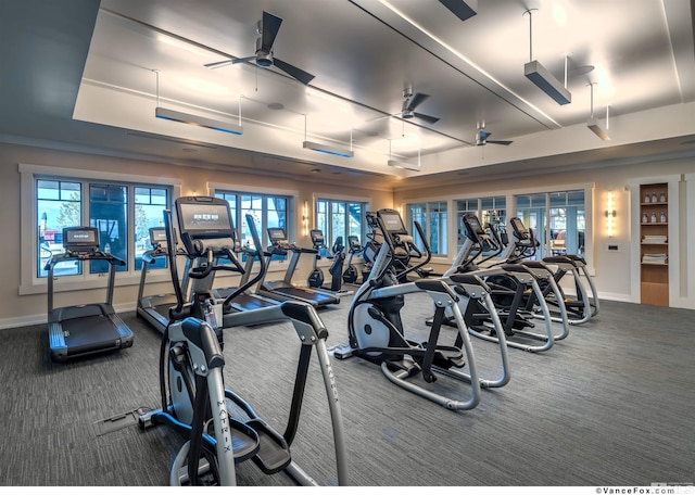 gym featuring a tray ceiling, ceiling fan, and carpet floors