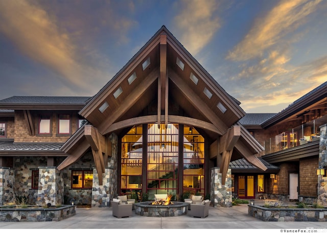 back house at dusk featuring an outdoor living space with a fire pit