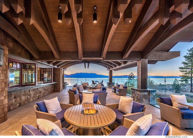 patio terrace at dusk featuring an outdoor living space and a water view