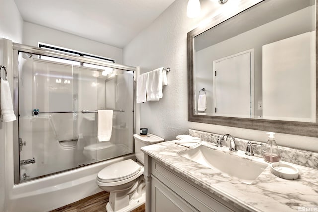 full bathroom featuring hardwood / wood-style flooring, toilet, vanity, and combined bath / shower with glass door