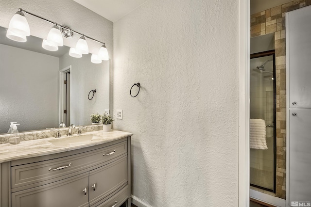 bathroom featuring a shower with door and vanity