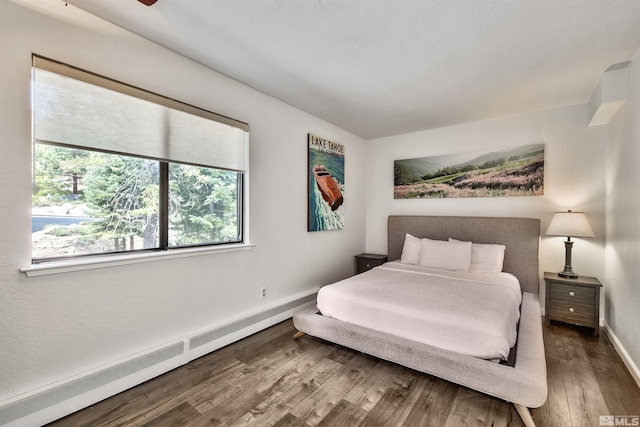 bedroom featuring wood-type flooring and a baseboard heating unit