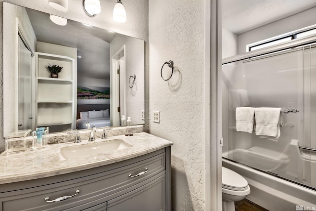 full bathroom with a textured ceiling, vanity, toilet, and bath / shower combo with glass door