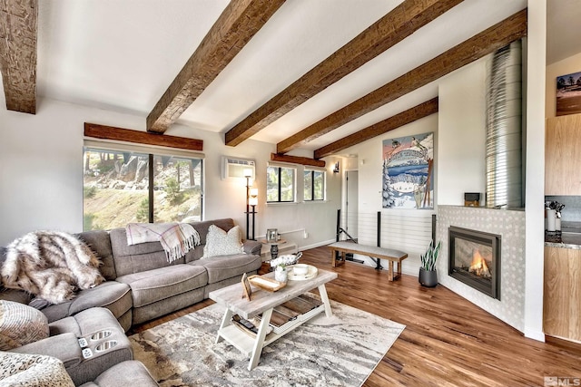 living room featuring hardwood / wood-style floors, lofted ceiling with beams, a tile fireplace, and a wall mounted AC