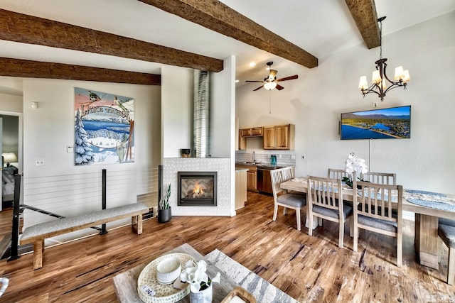 dining area featuring hardwood / wood-style flooring, ceiling fan with notable chandelier, sink, and beamed ceiling