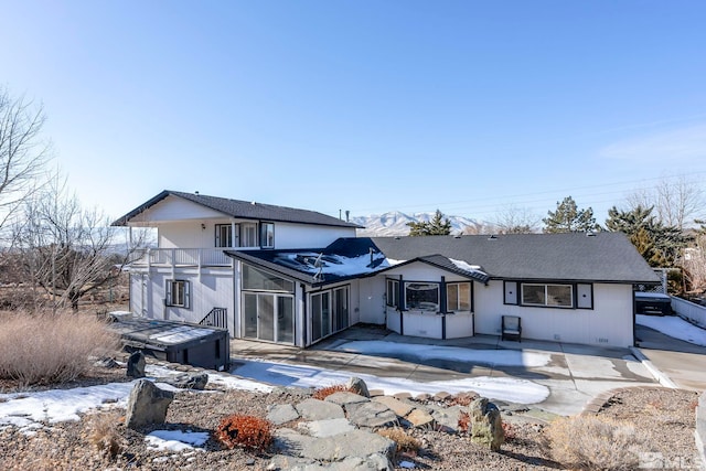 rear view of house featuring a balcony, a hot tub, and a patio area