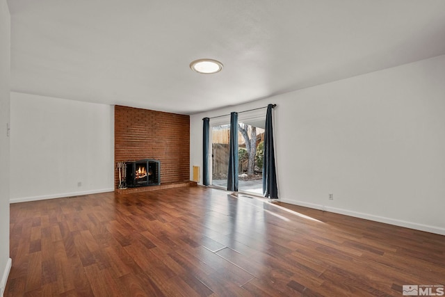 unfurnished living room featuring wood-type flooring and a brick fireplace